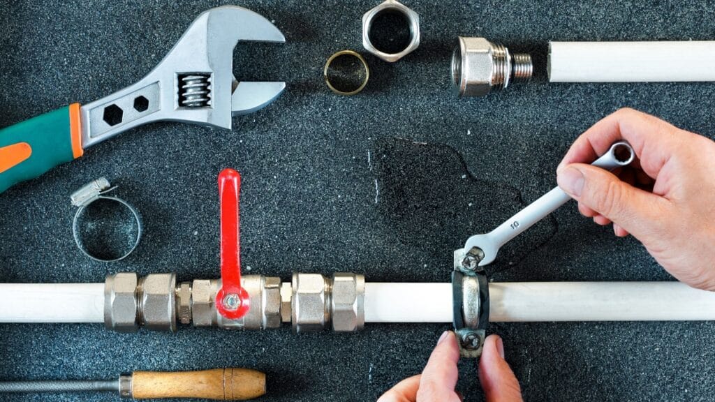 Plumber repairing a pipe valve with an adjustable wrench in Merritt Island