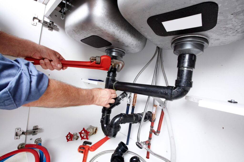 Plumber repairing drain pipes beneath a kitchen sink in Merritt Island