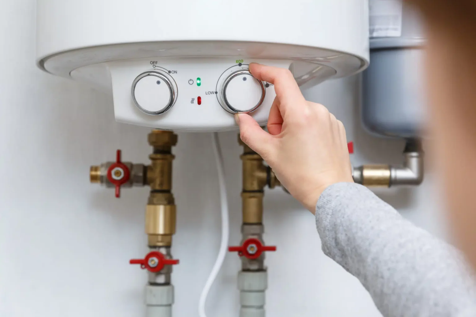 Homeowner adjusting the temperature controls on a water heater in Merritt Island